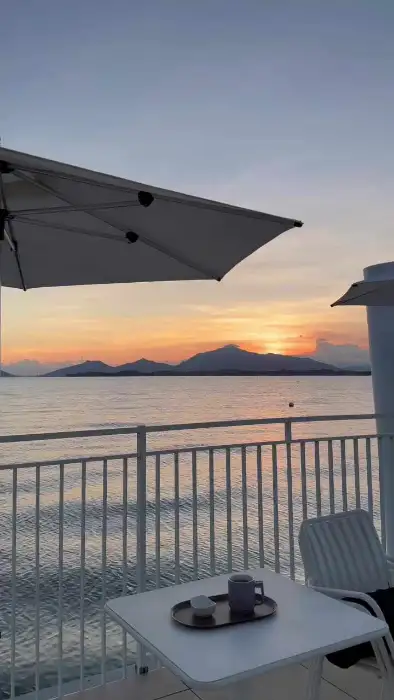 해 질 녘 바다와 산 능선, 그리고 테이블 위의 음료