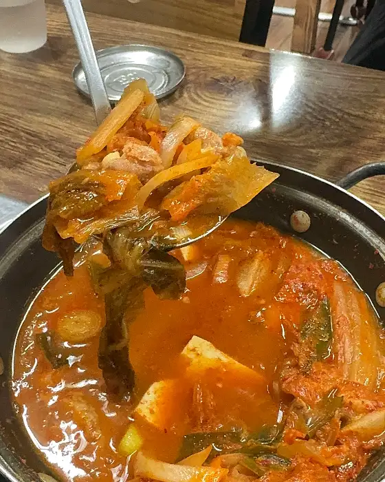 숟가락으로 김치찜 한 덩어리를 떠 올리는 모습