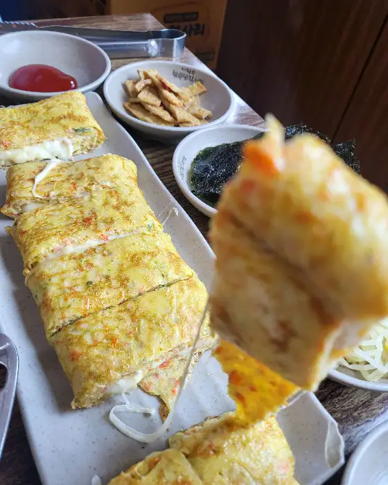 계란말이 여러 조각이 접시에 담겨 있고, 한 조각이 앞쪽으로 나와 있는 모습