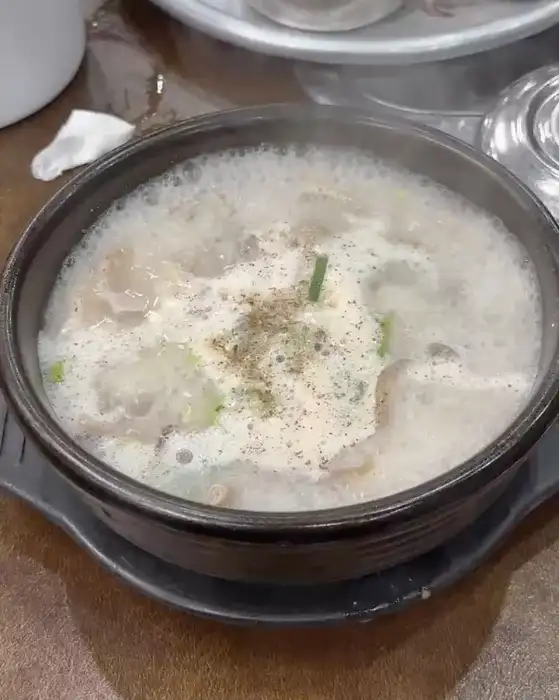 뽀얗고 진한 순대국밥 국물 위로 후추와 파가 뿌려져 있습니다.