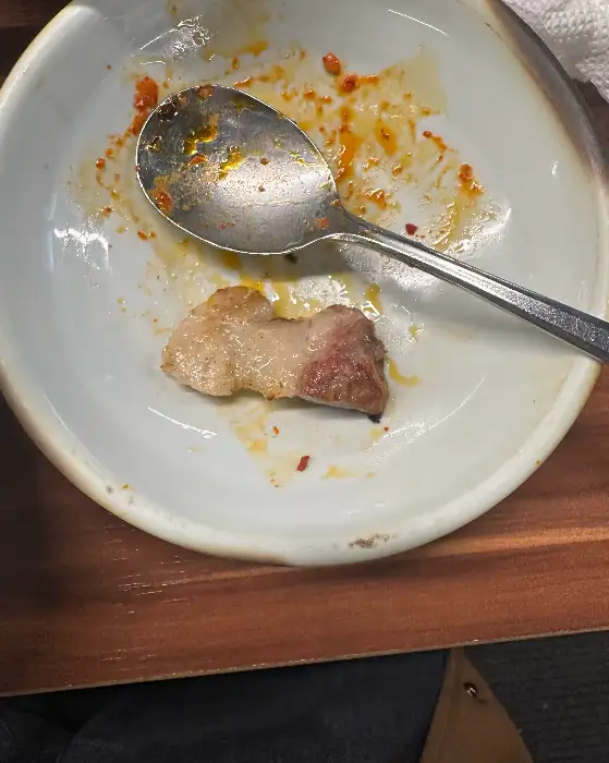접시에 담겨있는 삼겹살 한 점과 숟가락