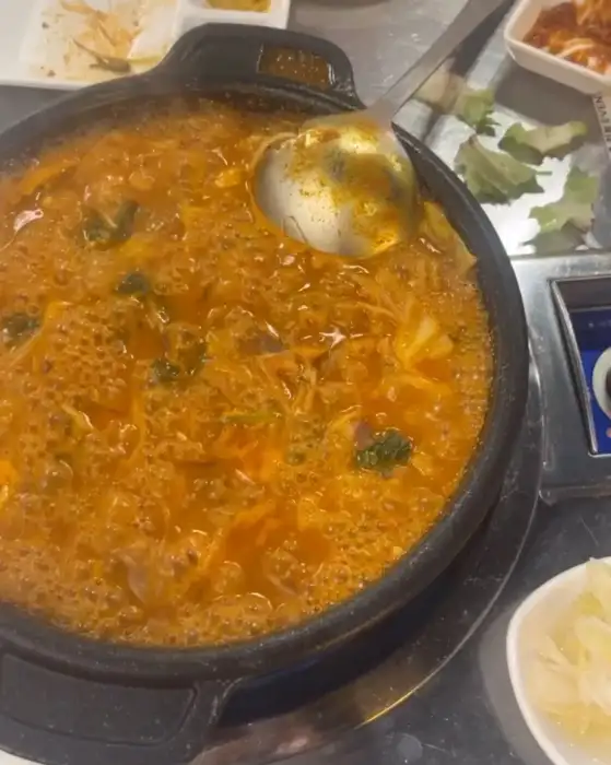 보글보글 끓고 있는 먹음직스러운 곱창전골. 건더기와 국물이 풍성하게 담겨 있습니다.