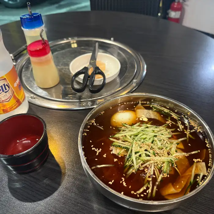 정갈하게 차려진 밀면 한 그릇과 곁들임 찬들