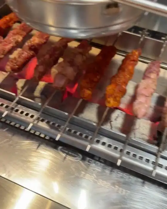 숯불 위에서 익고 있는 양꼬치 꼬치들