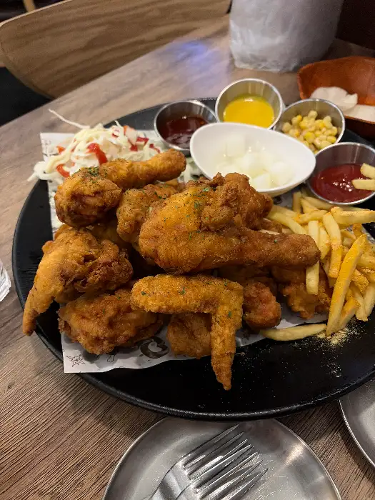 다양한 부위의 치킨과 감자튀김, 샐러드, 소스