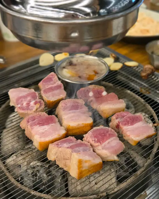 숯불 위에서 익어가는 돼지고기 덩어리들