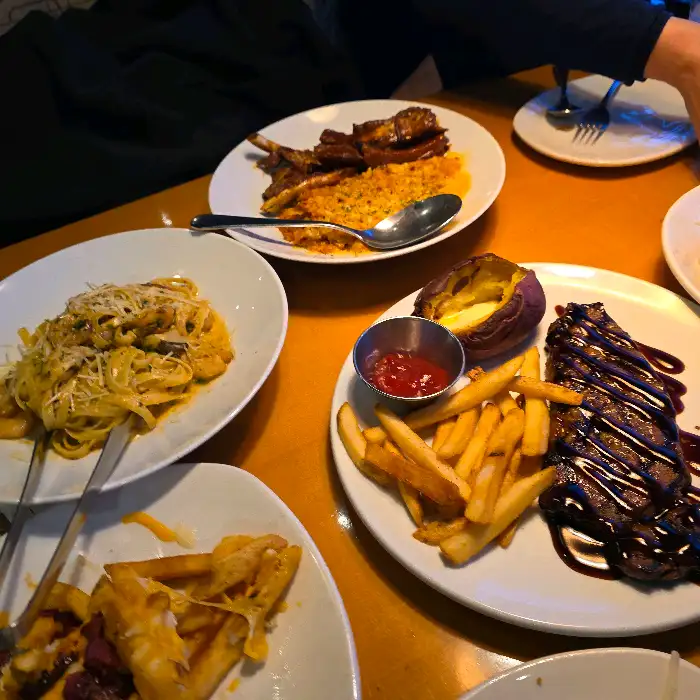 여러 접시에 담긴 다양한 음식들. 스테이크, 파스타, 감자튀김, 그리고 볶음밥 등이 보인다.