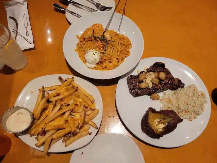 테이블 위에 놓인 다양한 스테이크와 파스타, 감자튀김.