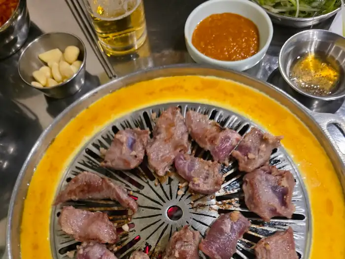 불판 위에 올라간 먹음직스러운 갈매기살과 곁들임 찬들.