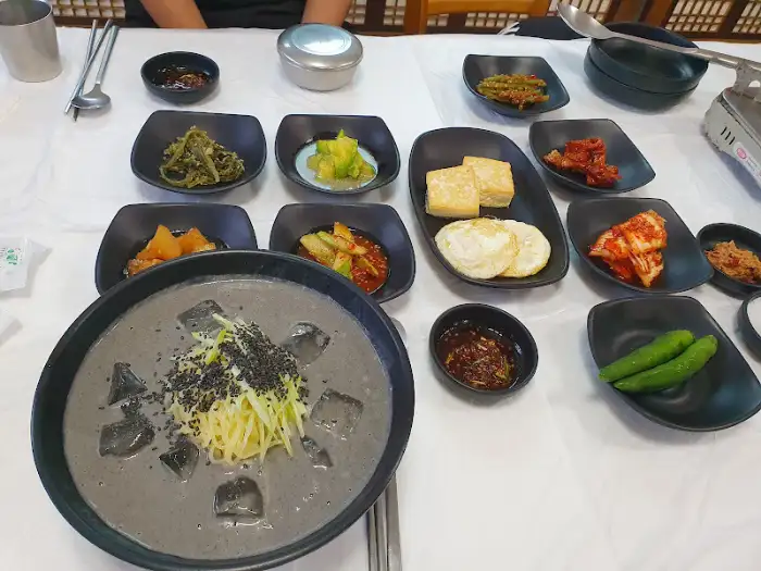 식탁에 놓인 국물 요리와 밑반찬들, 그리고 콩국수로 보이는 음식