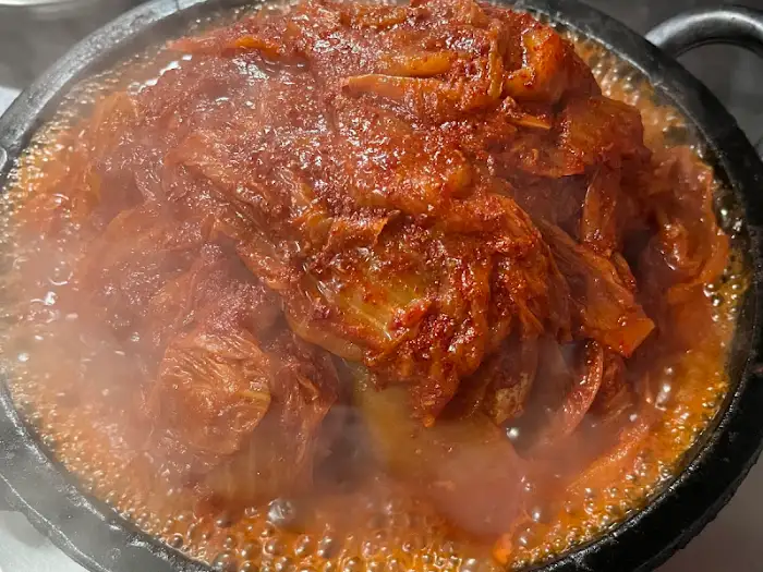 김이 피어오르는 고등어조림 클로즈업. 묵은지와 고등어살이 풍성하게 보인다.