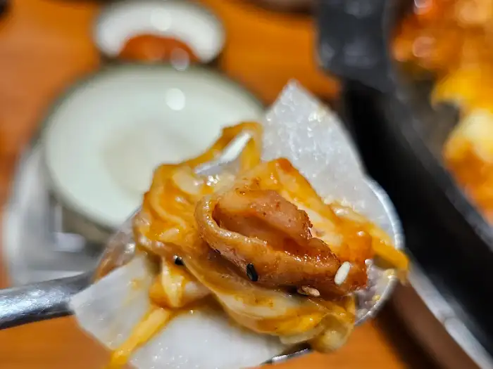 집게에 올려진 닭갈비와 치즈