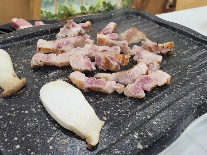 돌판 위에서 구워지는 삼겹살과 버섯