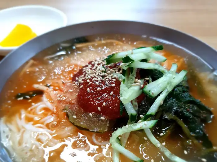 빨간 양념과 채소가 곁들여진 매콤한 국수