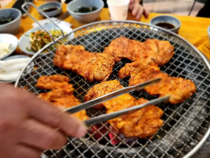집게로 닭갈비를 집는 손