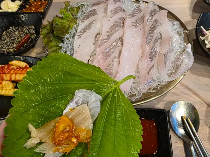 쌈 채소와 함께 놓인 회 한 점