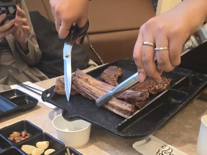 직원이 가위와 집게로 우대갈비 손질 중