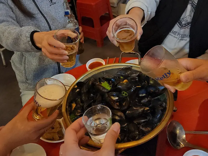 홍합탕을 앞에 두고 건배하는 사람들