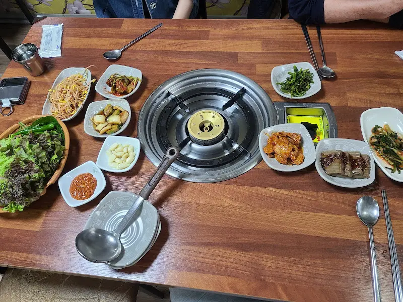 테이블 전체 샷, 다양한 반찬과 불판이 놓여있다.