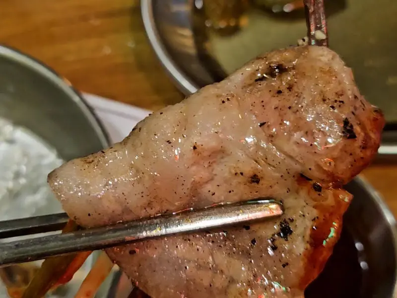 잘 구워진 고기를 젓가락으로 집은 모습