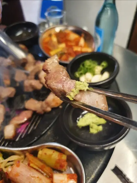 잘 익은 삼겹살 한 점을 집어 든 모습