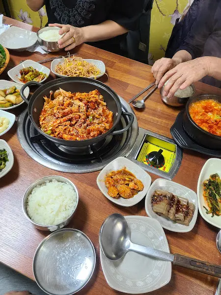 불판 위의 삼겹살과 반찬, 밥그릇 등이 놓인 테이블