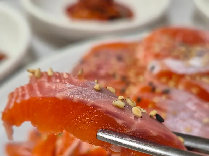 젓가락으로 집어 올린 송어회 한 점