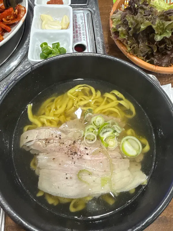 뽀얀 국물에 담긴 칼국수와 돼지고기가 식욕을 자극한다.