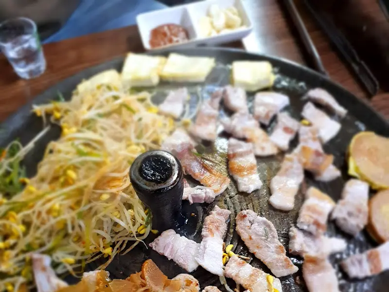 솥뚜껑 위에 올려진 삼겹살과 묵은지, 콩나물