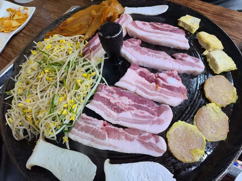 솥뚜껑 위에 올려진 삼겹살과 묵은지