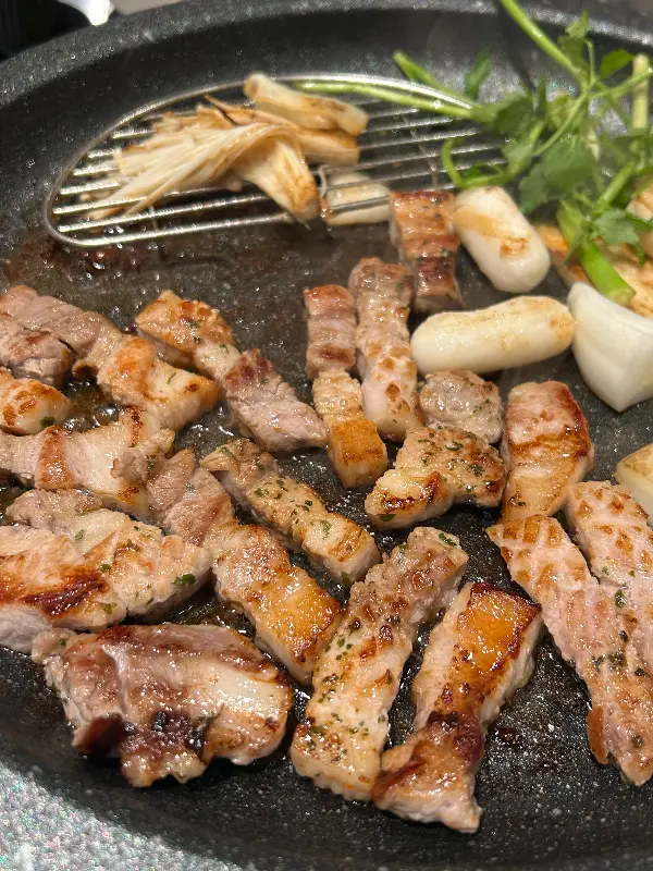 불판 위에서 맛있게 익어가는 삼겹살 조각들