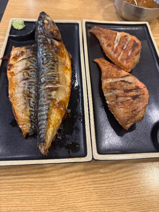 바삭하게 구워진 열기구이와 고등어구이의 클로즈업 사진. 윤기가 흐르는 생선 살이 먹음직스럽다.