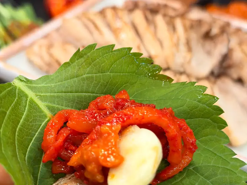 싱싱한 쌈 채소에 보쌈, 마늘, 쌈장을 얹어 한 쌈