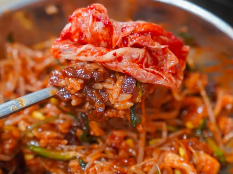 육회비빔밥 위에 김치를 올려 먹는 모습