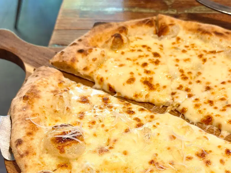 콰트로 포르마지 피자의 클로즈업 샷. 다양한 치즈가 녹아내려 먹음직스럽다.