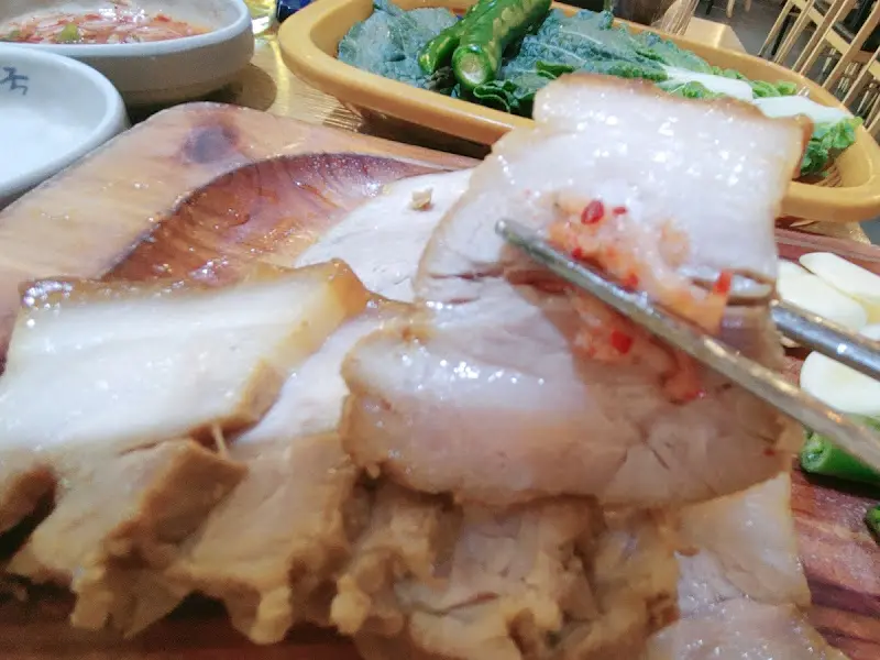 수육을 쌈에 싸서 먹는 모습