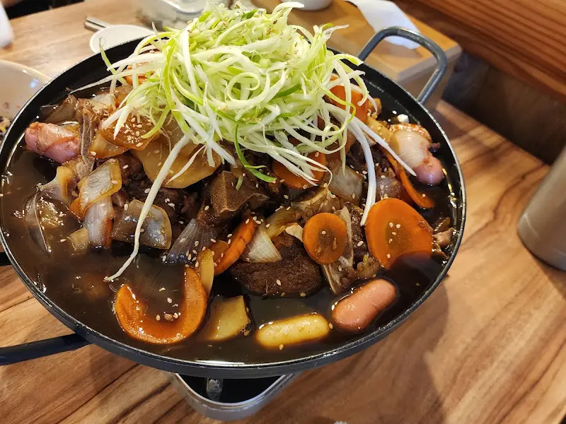 간장 뼈찜의 클로즈업 사진. 윤기가 흐르는 뼈다귀와 채소들이 먹음직스럽다.
