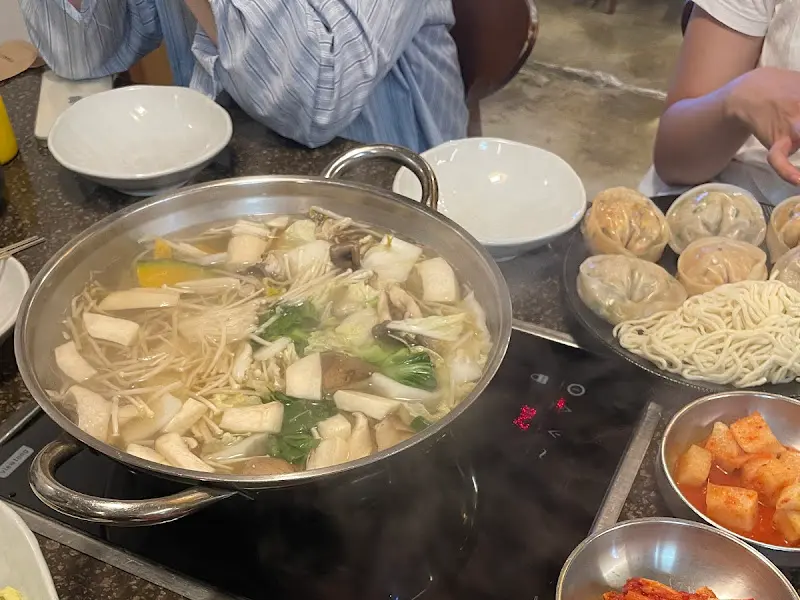 만두, 채소, 버섯이 듬뿍 들어간 만두전골이 테이블 위에서 보글보글 끓고 있는 모습