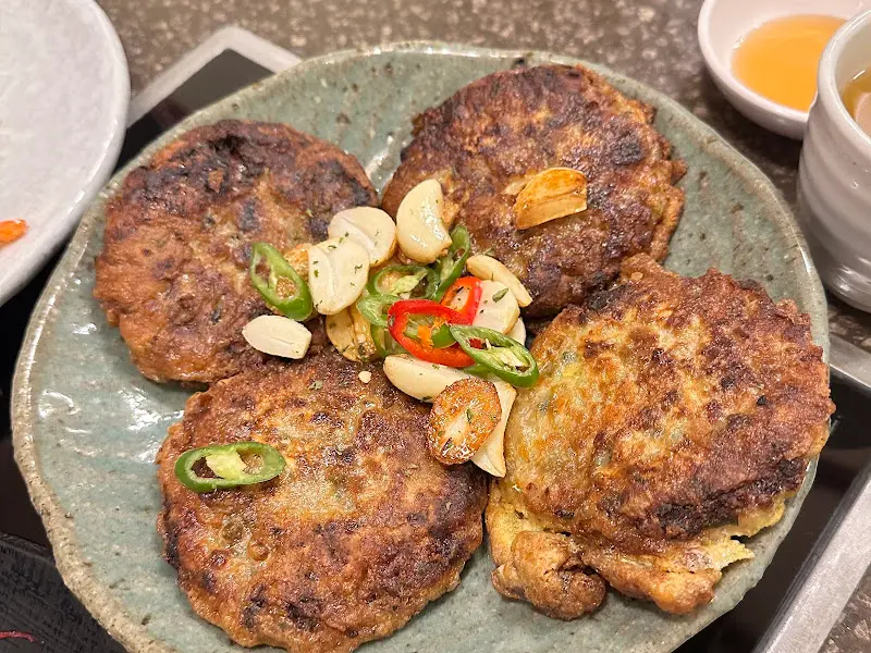 해물완자가 가운데에 놓여 있고, 구운 마늘과 고추가 가니쉬로 올려져 있는 모습