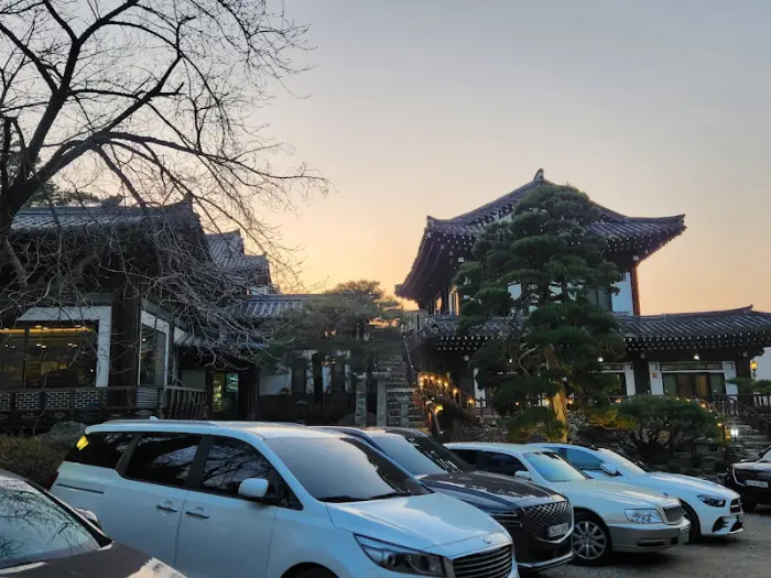 저녁 노을 아래 한옥 건물과 주차된 차량들