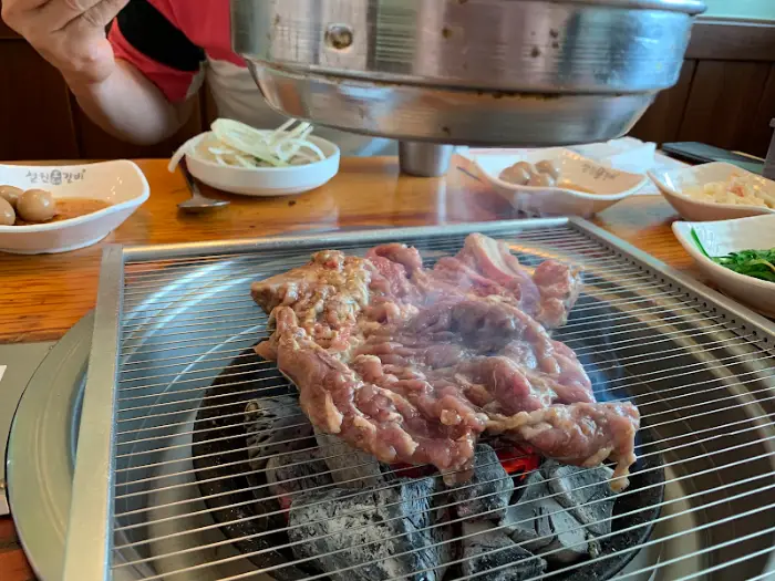 숯불 위에서 구워지고 있는 돼지갈비와 곁들임 채소