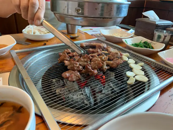 집게로 돼지갈비 조각을 뒤집는 모습