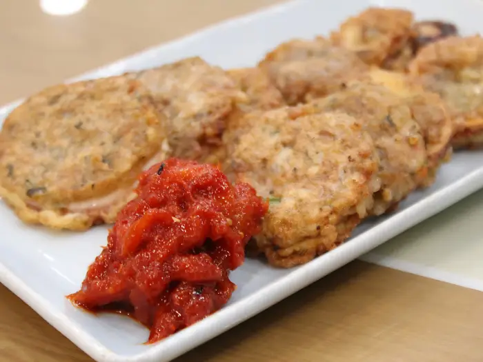 앞접시에 담긴 붉은 양념과 함께 놓인 노릇하게 구워진 감자전.