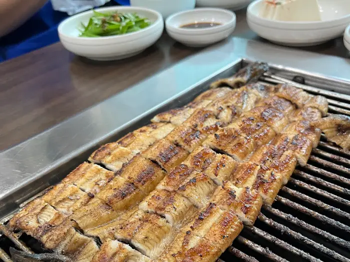 그릴 위 먹음직스럽게 구워진 장어와 곁들임 찬