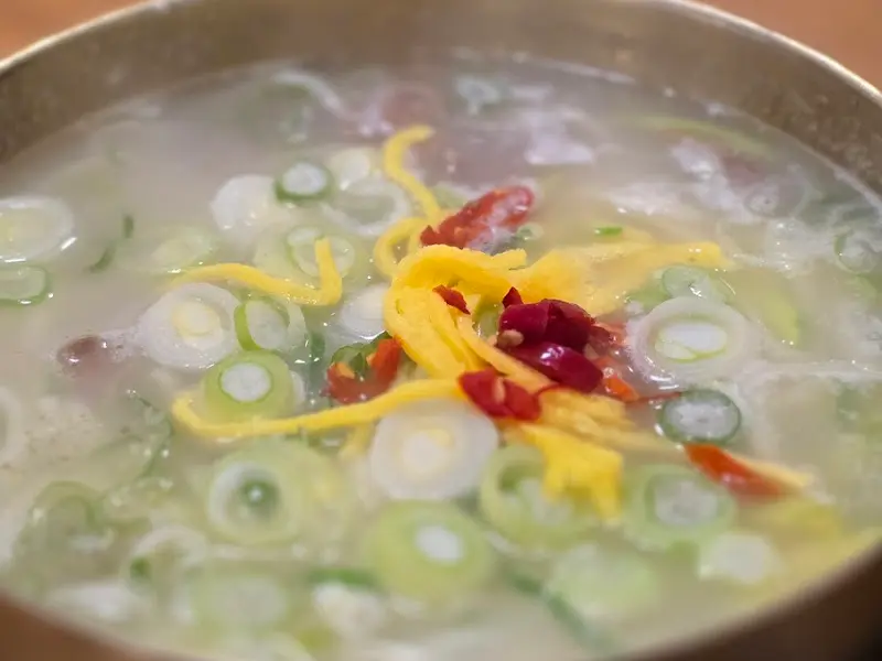 뽀얀 사골 육수에 파, 김가루, 고기가 올라간 칼국수의 모습