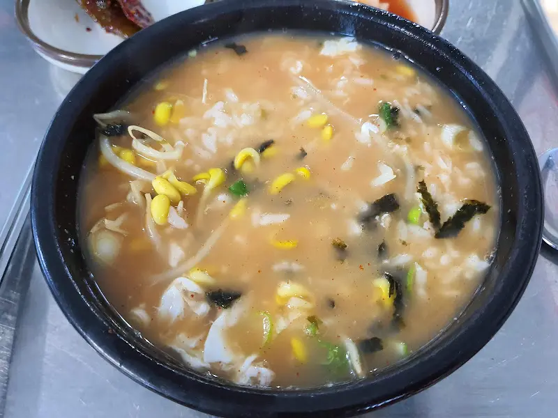 쟁반 위에 놓인 콩나물국밥, 깍두기, 고추장아찌