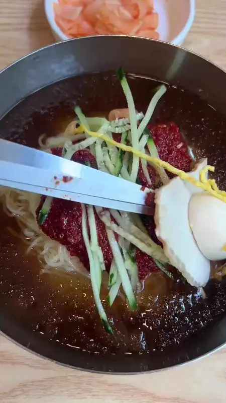 밀면을 가위로 자르는 장면