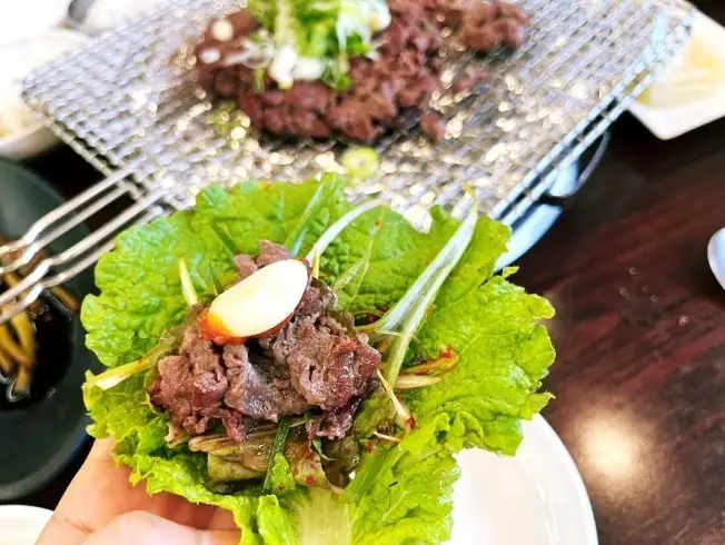 불고기를 쌈으로 싸서 든 손