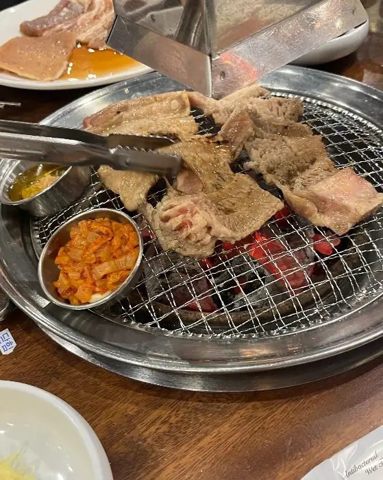 식탁 위에서 구워지고 있는 고기와 곁들임 찬