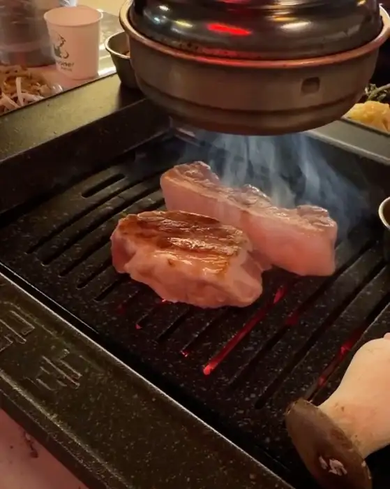 숯불 위에서 맛있게 익어가고 있는 두툼한 돼지고기 덩어리